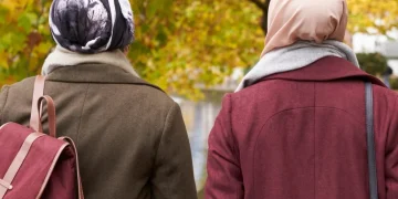 Due donne con velo islamico camminano in un parco autunnale