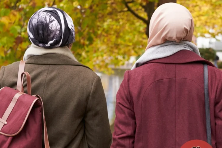 Due donne con velo islamico camminano in un parco autunnale