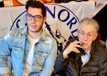Renzo Bossi e Umberto Bossi seduti insieme, il padre fuma un sigaro.