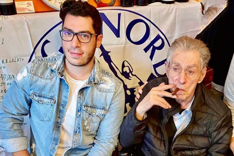 Renzo Bossi e Umberto Bossi seduti insieme, il padre fuma un sigaro.