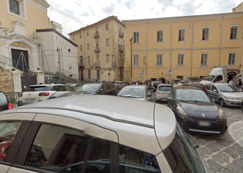 Strada trafficata con auto parcheggiate in Largo Tommaso D'Aquino, Salerno. Accoltellata alle spalle da uno sconosciuto, grave una 20enne