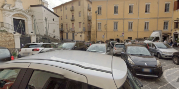 Strada trafficata con auto parcheggiate in Largo Tommaso D'Aquino, Salerno. Accoltellata alle spalle da uno sconosciuto, grave una 20enne