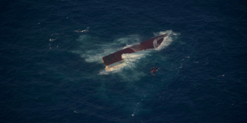 Traghetto passeggeri capovolto in mare con persone in salvagente arancioni. Indonesia, il maltempo blocca i soccorsi: oltre 100 dispersi dopo il naufragio della Virgo Transport