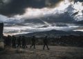 A group of soldiers march through a rugged landscape under a threatening sky in Israel.