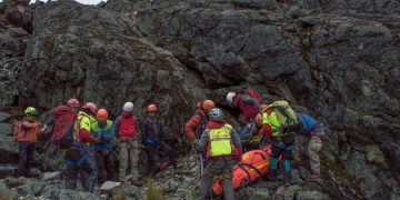 A rescue team aids an injured hiker on a rocky mountain slope during daylight. Speleologo intrappolato in una grotta in Sardegna, soccorritori al lavoro da ore