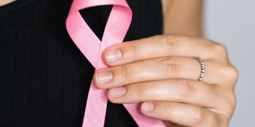 Close-up of a woman holding a pink ribbon for breast cancer awareness. Screening mammografico, 4 donne su 10 dichiarano di non aver mai ricevuto l’invito