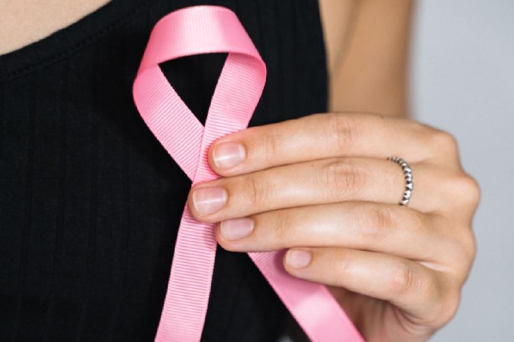 Close-up of a woman holding a pink ribbon for breast cancer awareness. Screening mammografico, 4 donne su 10 dichiarano di non aver mai ricevuto l’invito