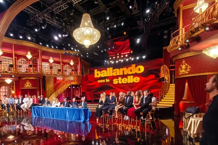Palco Ballando con le Stelle con giudici e concorrenti seduti, luci brillanti.