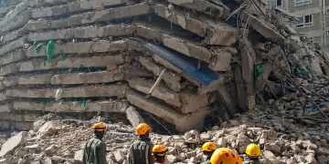 Soccorritori con caschi gialli osservano le macerie dell'edificio crollato. Nairobi, crolla un palazzo di oltre 10 piani: persone intrappolate sotto le macerie
