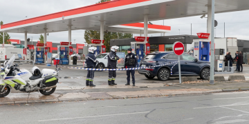 Agenti di polizia delimitano una stazione di servizio con nastro segnaletico. Francia, un uomo apre il fuoco a Trappes: un morto e quattro feriti. Lecornu: "Fatti gravi"