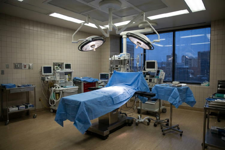 sala operatoria vuota, con il lettino chirurgico al centro, le lampade accese e nessun medico presente
