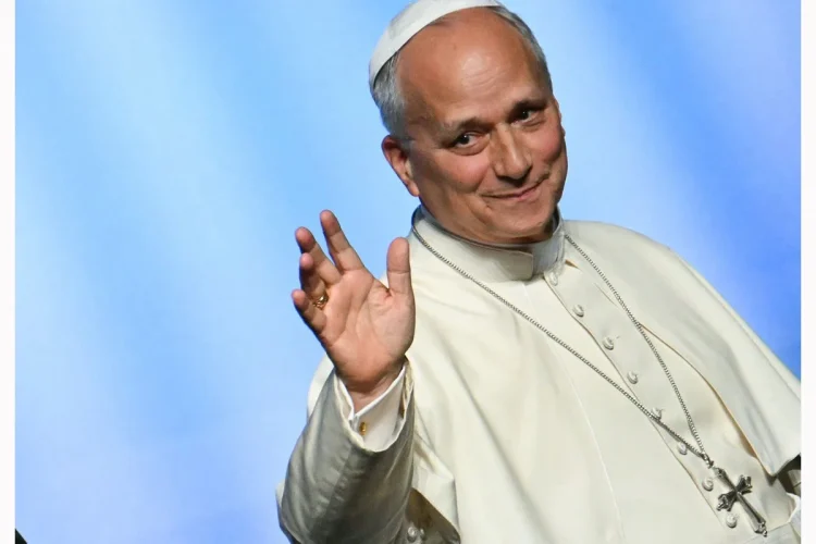 Papa Leone XIV sorride e saluta indossando abiti papali bianchi.
