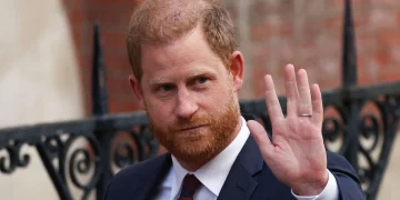 Il principe Harry in abito scuro saluta con la mano