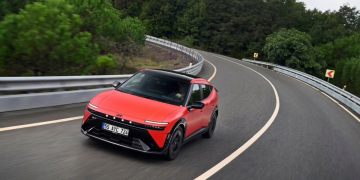 SUV Hyundai rosso compie una curva su strada asfaltata panoramica. Car of the Year 2027, la finale è per la prima volta tutta elettrica