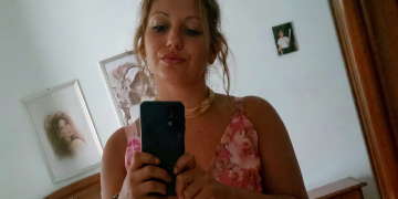Donna dai capelli mossi si scatta un selfie allo specchio con smartphone. Morte Noemi Impellizzeri, la corda al collo sotto analisi Ris. I legali: "Potrebbe esserci il DNA dell'assassino"