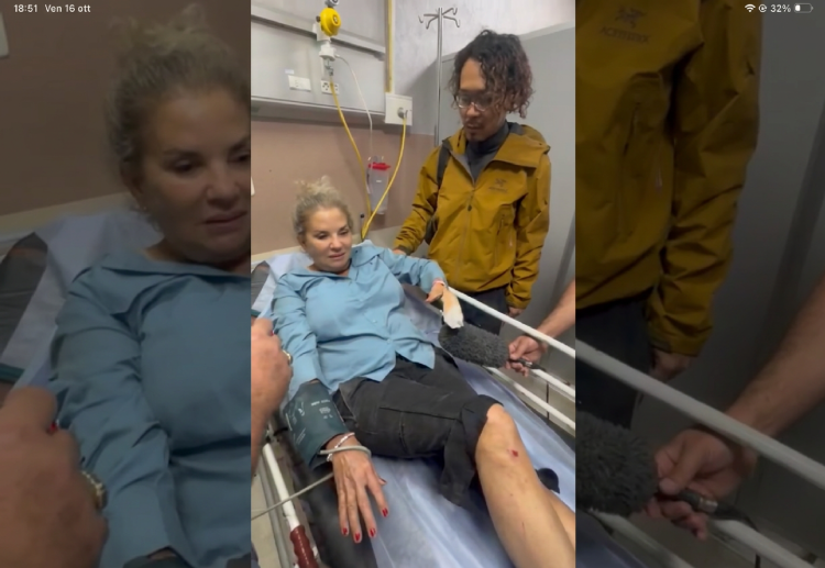 Donna ferita su barella intervistata con microfono in ospedale, uomo vicino.