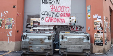Striscione di protesta appeso sopra cassonetti dell'immondizia ribaltati. Occupazioni a Bologna: la protesta nelle scuole contro guerra e carovita si allarga