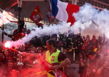 Studenti francesi in protesta accendono fumogeni rossi durante manifestazione