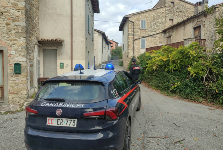 Auto dei Carabinieri parcheggiata in una strada tra case in pietra. Tortona, bimba di 3 anni trovata morta in casa: arrestata la madre