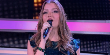 Nicla Ozenda canta al microfono in studio televisivo. La ruota della fortuna, la cantante Nicla Ozenda si ferma per un intervento alle corde vocali