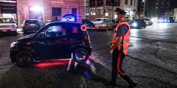Carabiniere in strada ferma piccola auto nera con luci lampeggianti. Banda delle minicar, il minorenne a Pm e carabinieri: "Era uno scherzo"