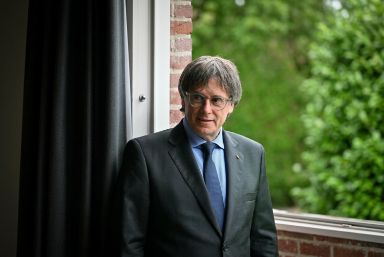 Carles Puigdemont in abito scuro guarda pensieroso fuori da una finestra. Puigdemont può tornare in Spagna: il Tribunale Supremo revoca l'ordine di arresto